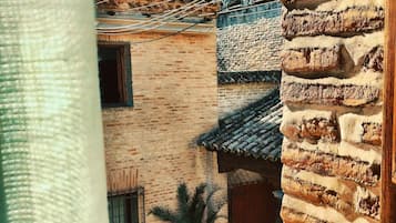 A courtyard with a stone wall, a tiled roof, and a palm tree.
