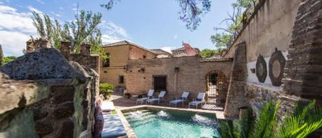 A pool area with stone walls, lounge chairs, and a clear blue pool.