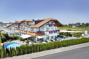 Un edificio residencial de varios pisos con piscina, mobiliario exterior y un jardín bien cuidado.