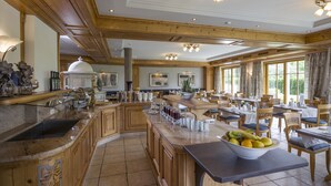 Una cocina amplia con una isla grande, armarios de madera y un comedor con mesas y sillas.