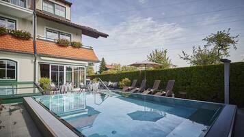 Relax by the rooftop pool surrounded by lounge chairs and lush greenery.