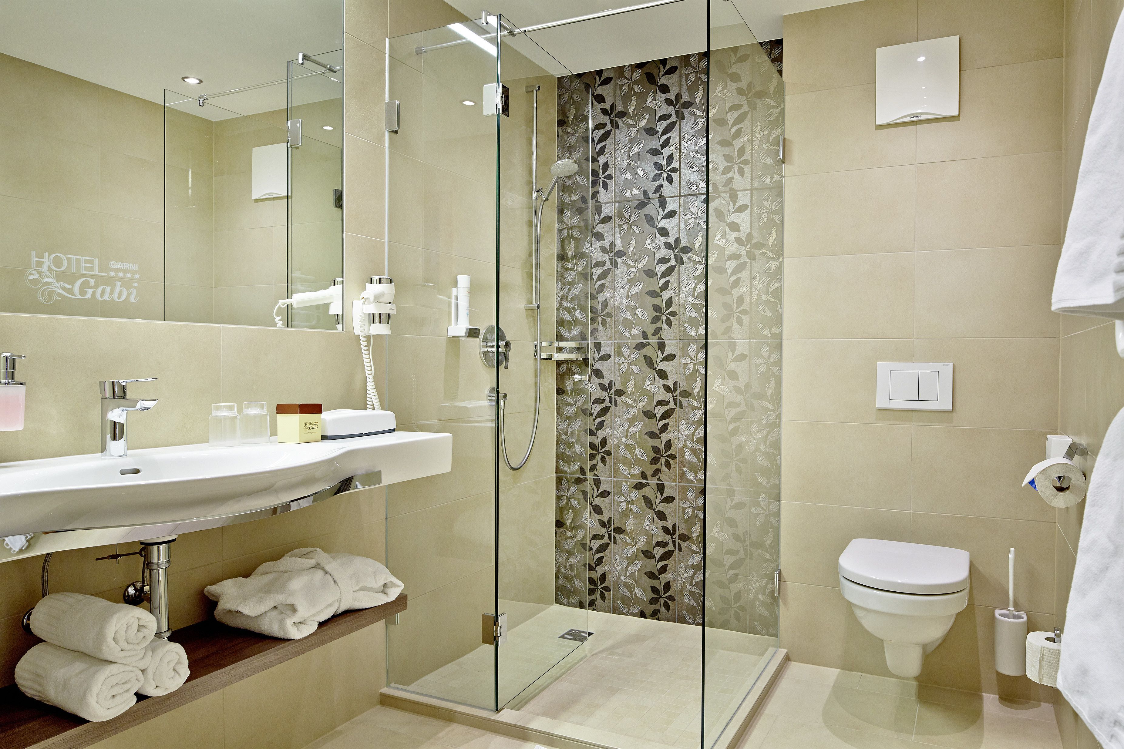 A modern bathroom with a glass-enclosed shower, a sink with toiletries, and a toilet.
