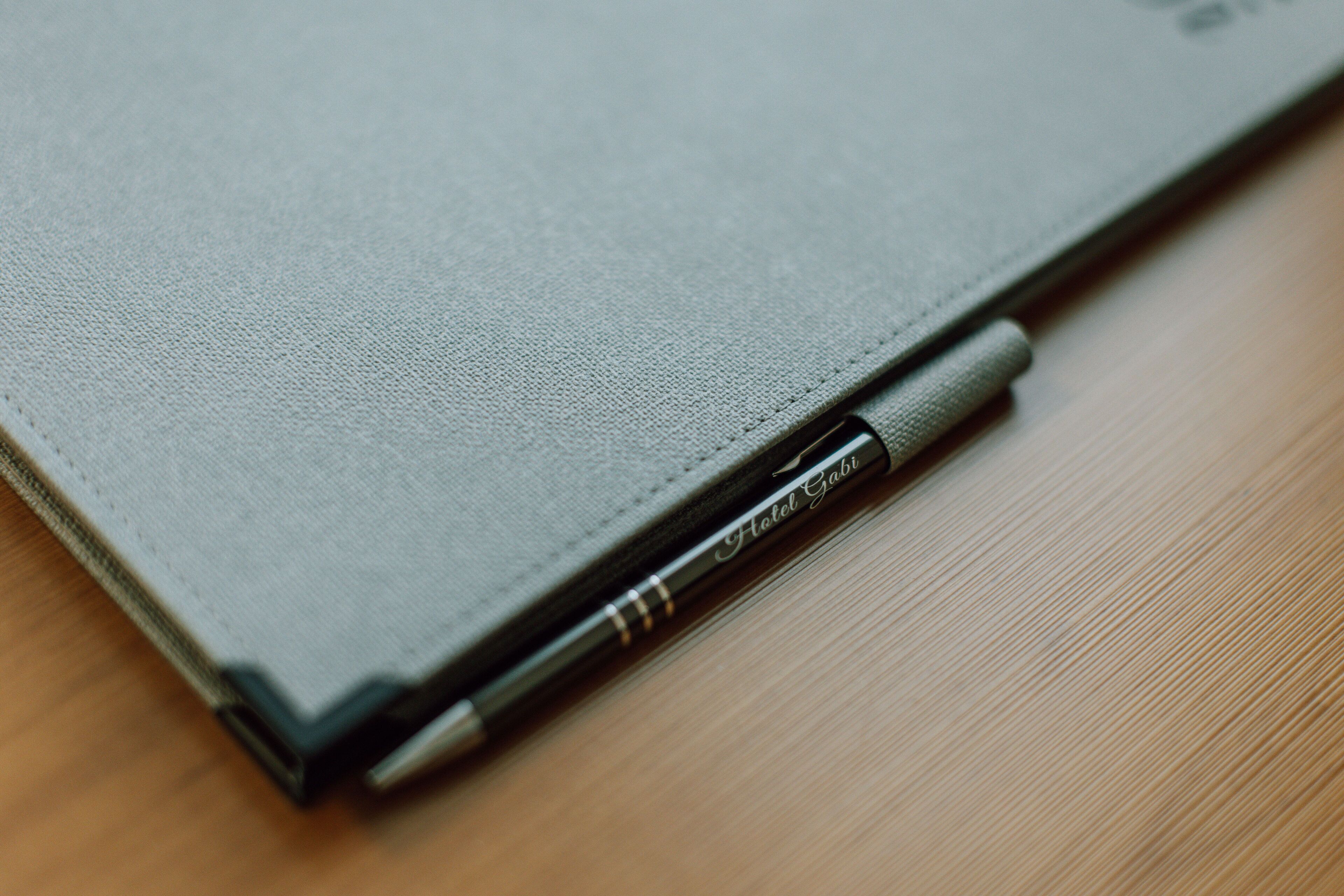 A closed laptop with a pen inserted into its side.