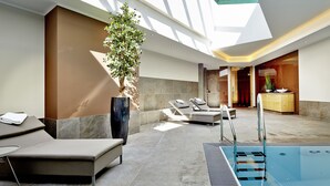 Un área de piscina interior moderna con asientos iluminados por el sol y una vista despejada del cielo.