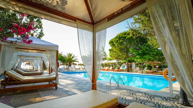 A poolside area with sun loungers and a pool. - Summery Hotel (Kefalonia)