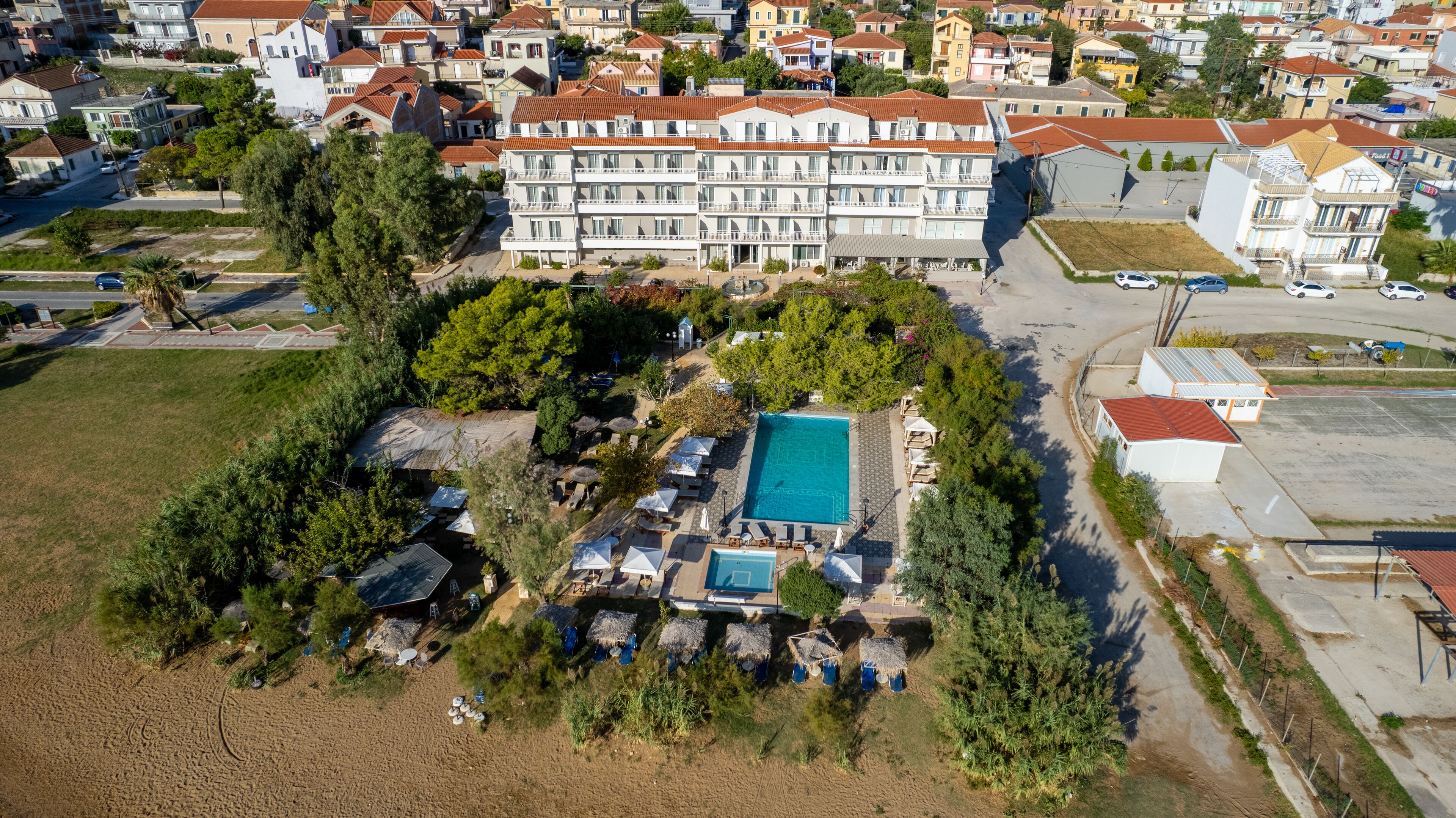 Vista aérea de una zona residencial con un edificio grande con varios balcones, piscina y abundante vegetación.