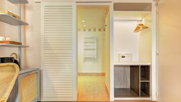A modern bathroom with a shower, a toilet, and a sink. There is a towel rack and a small shelf with toiletries.