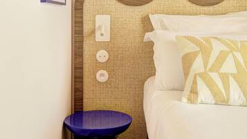 Ein Hotelzimmer mit Bett, Nachttisch, Wandleuchte und einem Bilderrahmen.