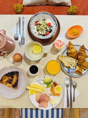 A breakfast table with various food items, including croissants, a slice of quiche, and a plate with ham and cheese. - Hôtel Gabriel - Nouveauté 2025 (Menton)