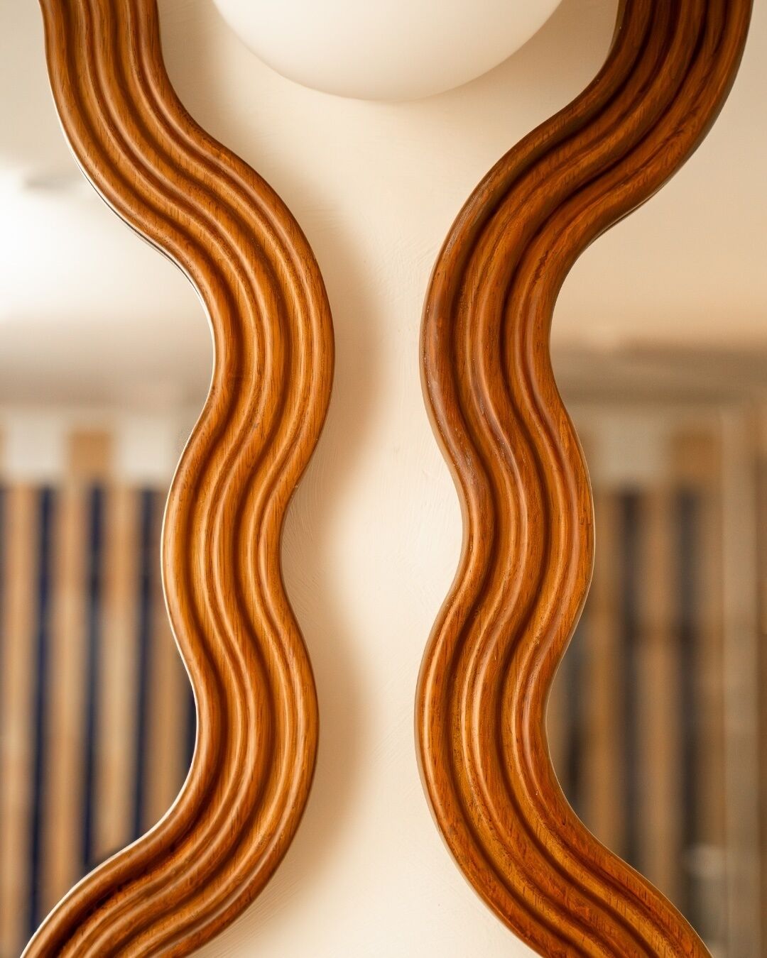 Un miroir en bois à fixer au mur, doté d’un motif ondulé.
