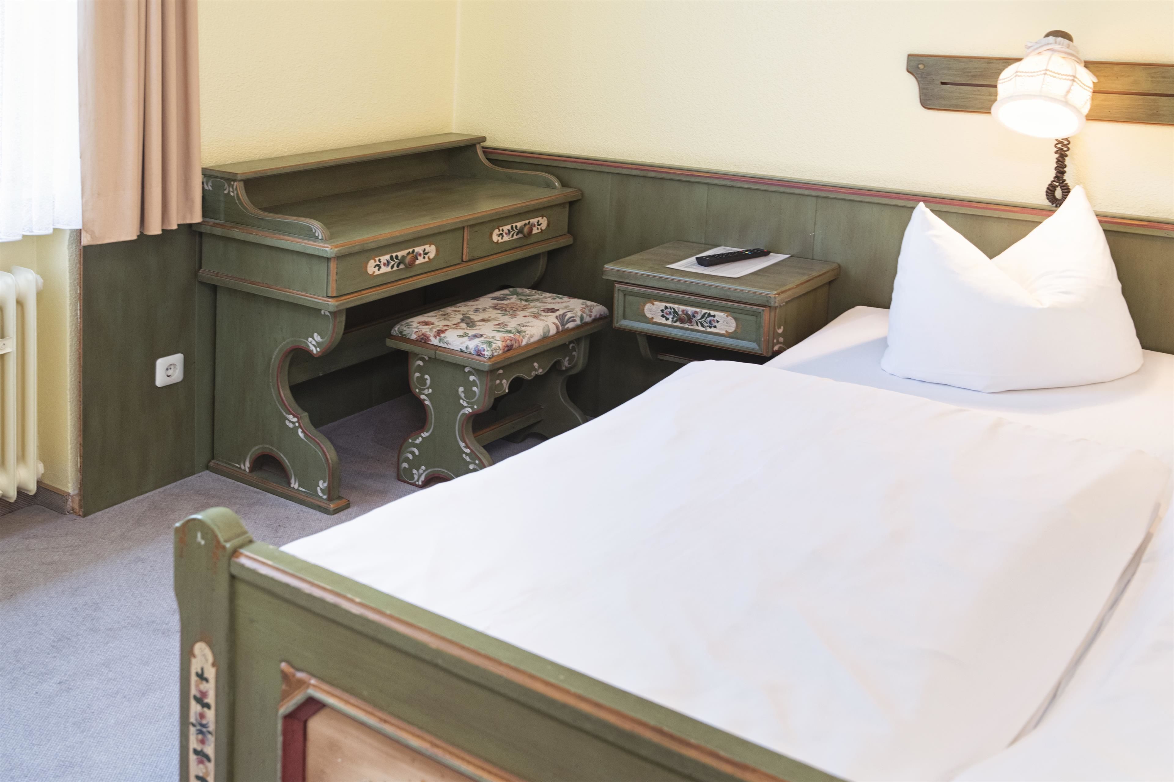 A room with a bed, a nightstand, a dresser, and a lamp.