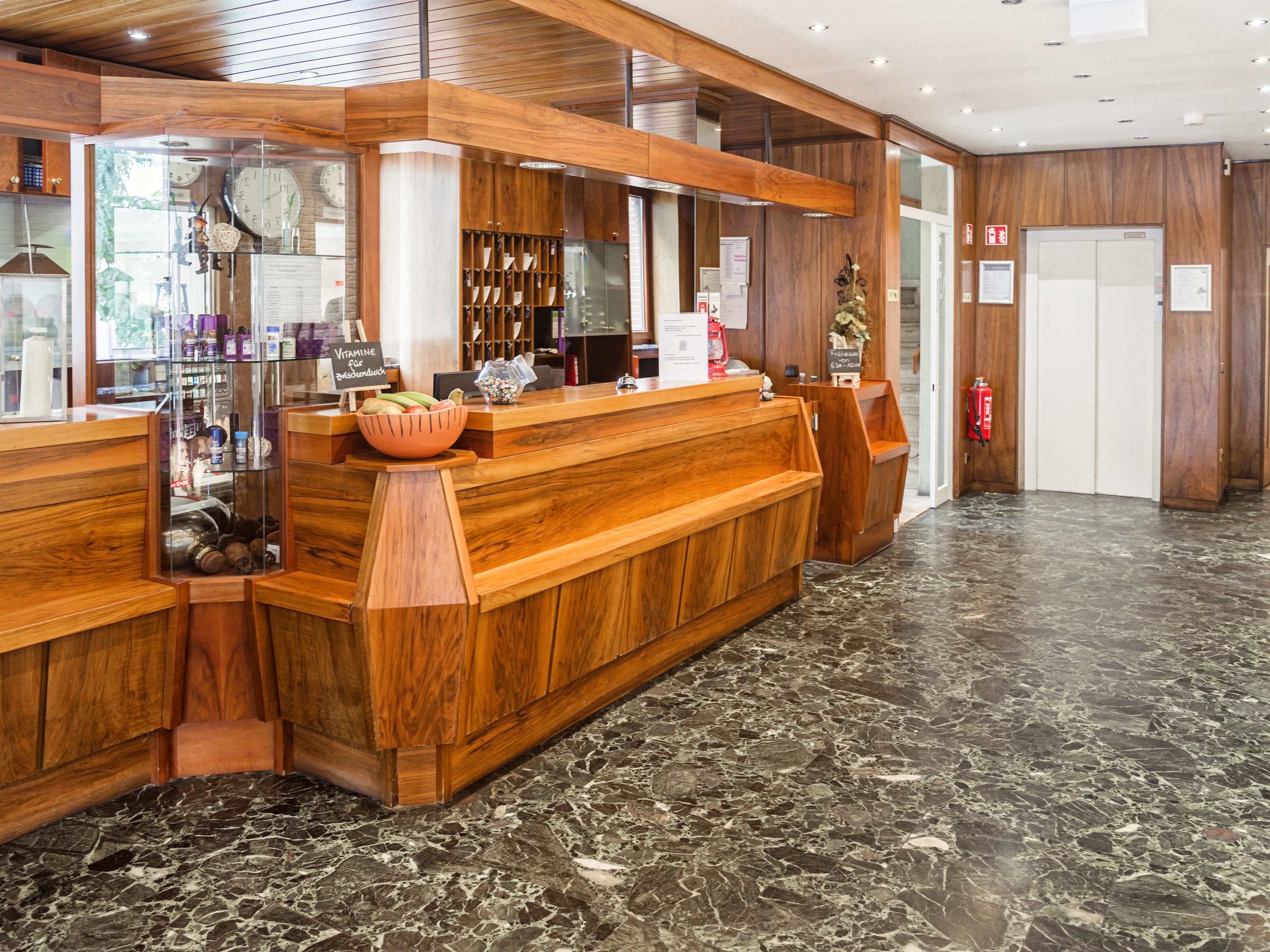 A reception area with a wooden counter, a glass display case, and a marble floor.