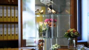 Un mostrador de recepción con una vitrina de vidrio que contiene flores y objetos decorativos.