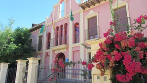 A pink building with balconies and a sign that reads "Hotel".