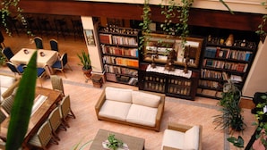 A cozy indoor seating area with a sofa, chairs, and a table, surrounded by bookshelves filled with books.