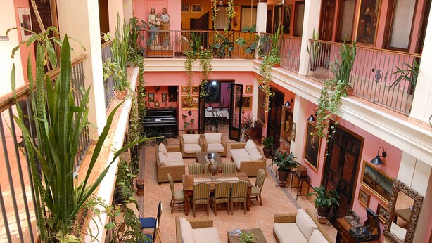 A multi-level atrium with a central seating area, surrounded by potted plants and artwork.