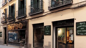 Un edificio con una tienda de regalos llamada 'Madrid Gift Shop' y un café llamado 'Blume'.