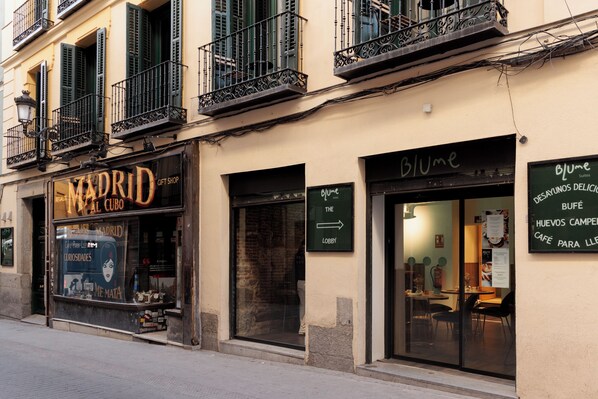 Un edificio con una tienda de regalos llamada 'Madrid Gift Shop' y un café llamado 'Blume'.