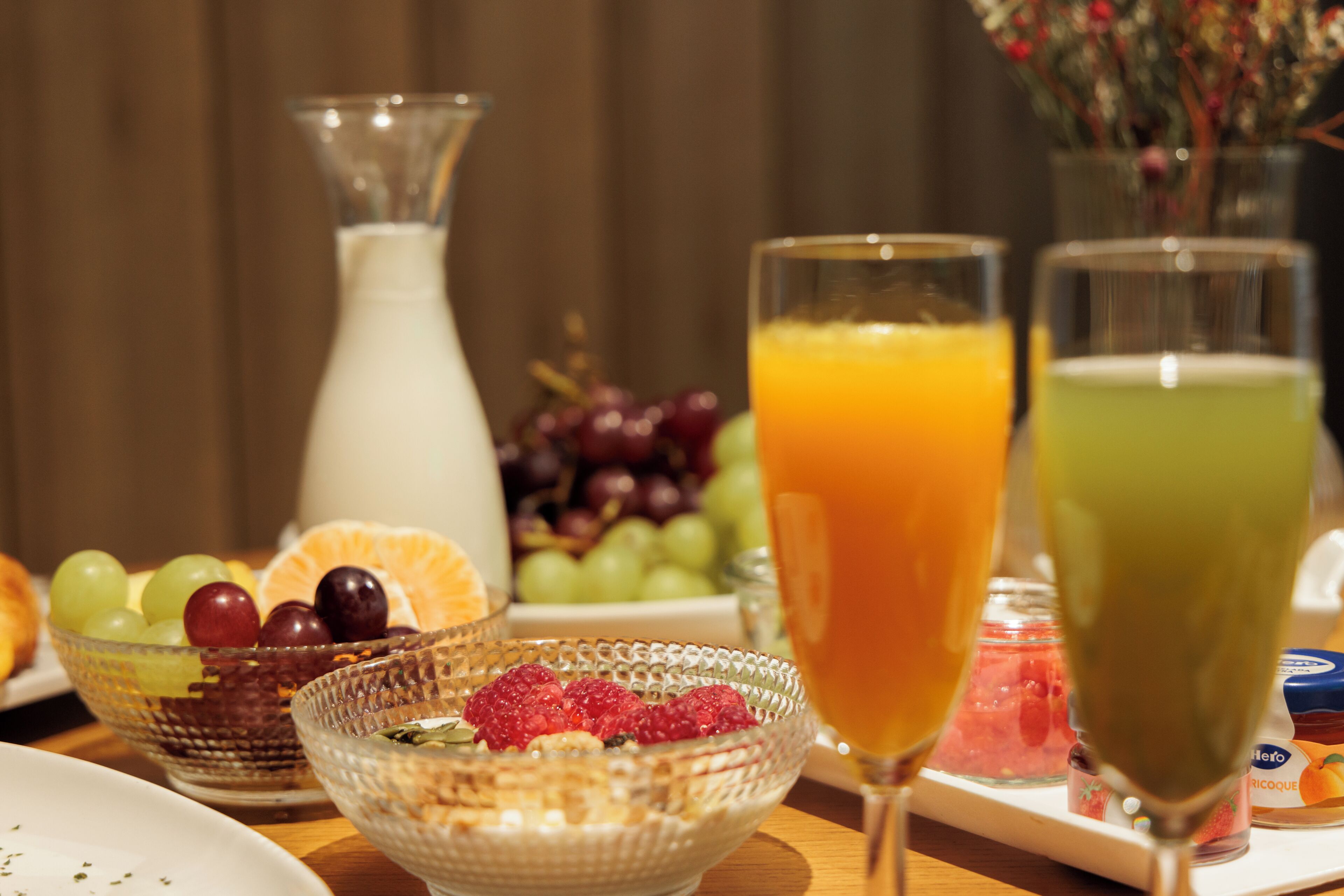Een ontbijttafel met een glazen kan, schalen met fruit en glazen jus d'orange.