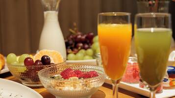 Een ontbijttafel met een glazen kan, schalen met fruit en glazen jus d'orange.