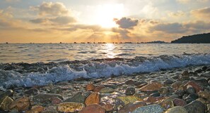 Una costa rocosa con olas y un atardecer sobre el agua.