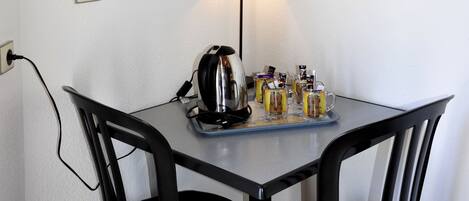 A small dining area with a table, chairs, a lamp, and a wall-mounted artwork.