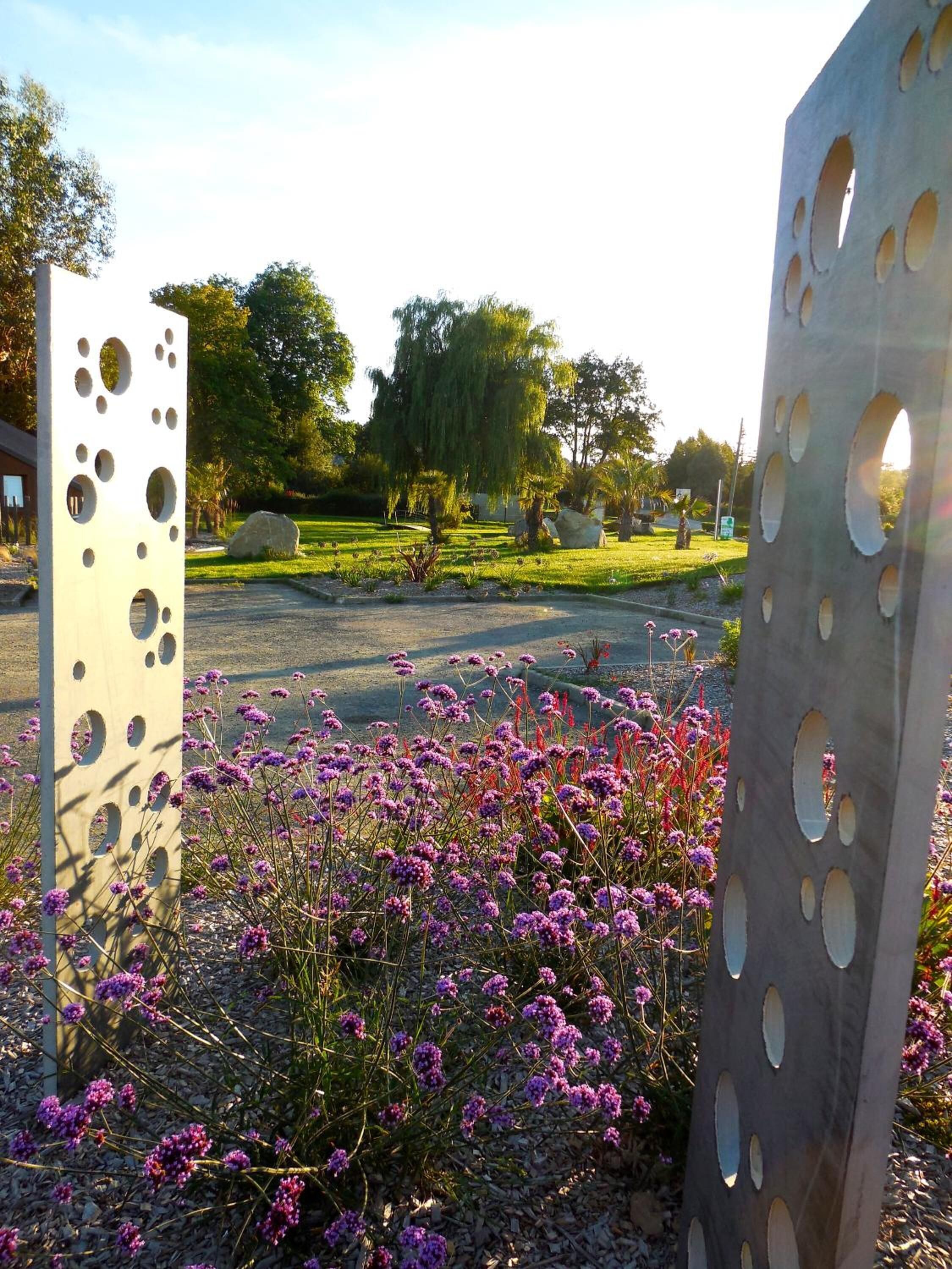 A garden with metal sculptures and purple flowers.