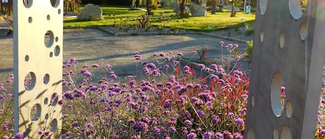 Un jardin agrémenté de sculptures en métal et de fleurs violettes.