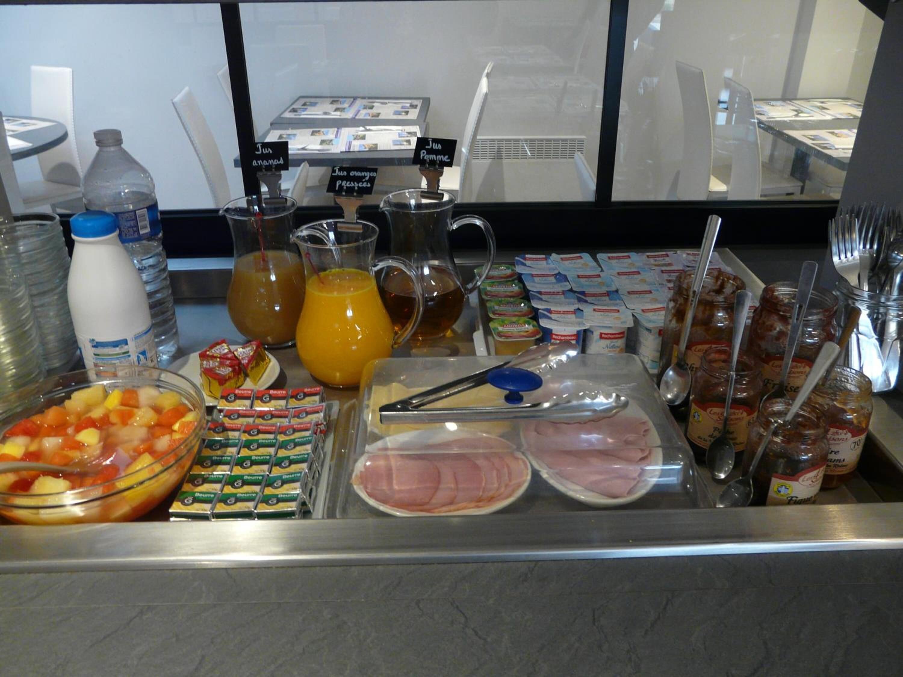 A buffet with various food items including fruits, juices, and condiments.