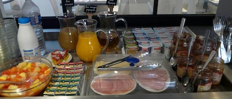 A buffet with various food items including fruits, juices, and condiments.