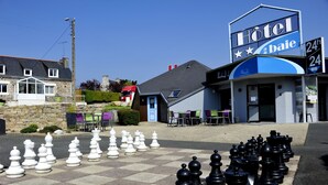Un hotel con un gran ajedrez al aire libre y mobiliario exterior.