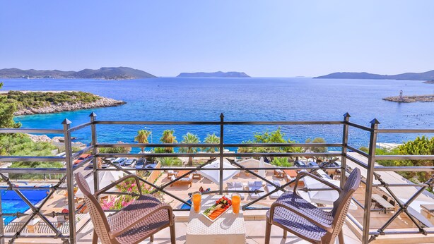A balcony with a view of the sea, lounge chairs, a table with a fruit platter and drinks, and a pool in the background. - Hera Hotel Kas (Kaş)