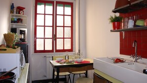 Une cuisine compacte avec une fenêtre à cadre rouge, un évier et un coin repas avec des chaises.