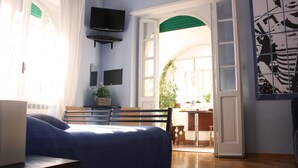 Une chambre à coucher avec un lit, un bureau, une télévision et une vue sur l’extérieur.