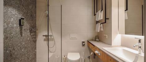 A modern bathroom with a shower, toilet, and sink.