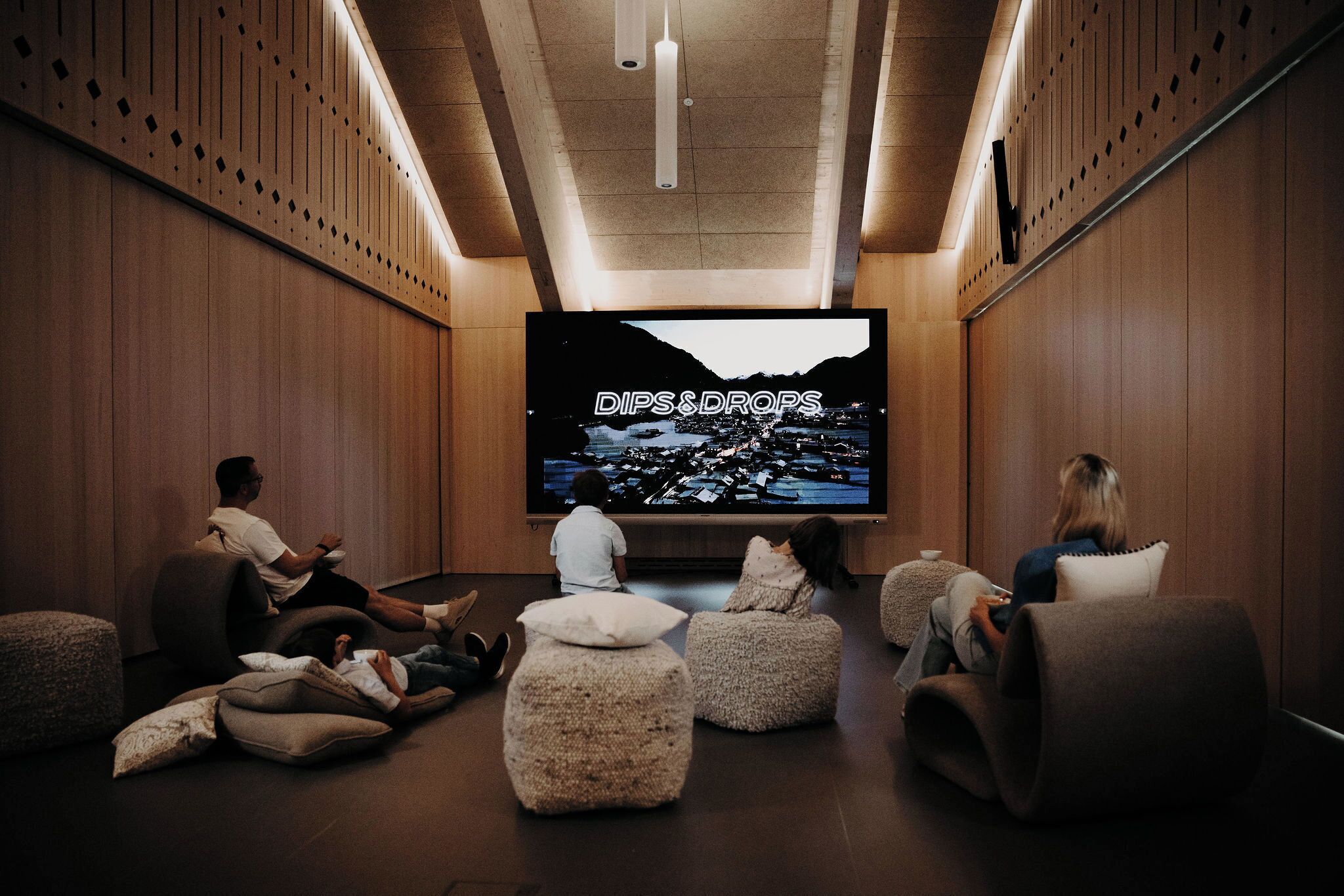 A modern interior with wooden paneling, a large flat-screen TV, and comfortable seating areas.