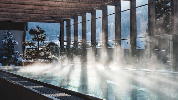 A steam room with large windows, a wooden ceiling, and a view of a snowy landscape. - Dips&Drops – SUPERIOR HOTEL · SPORTS · SPA · RESTAURANTS (Flachau)