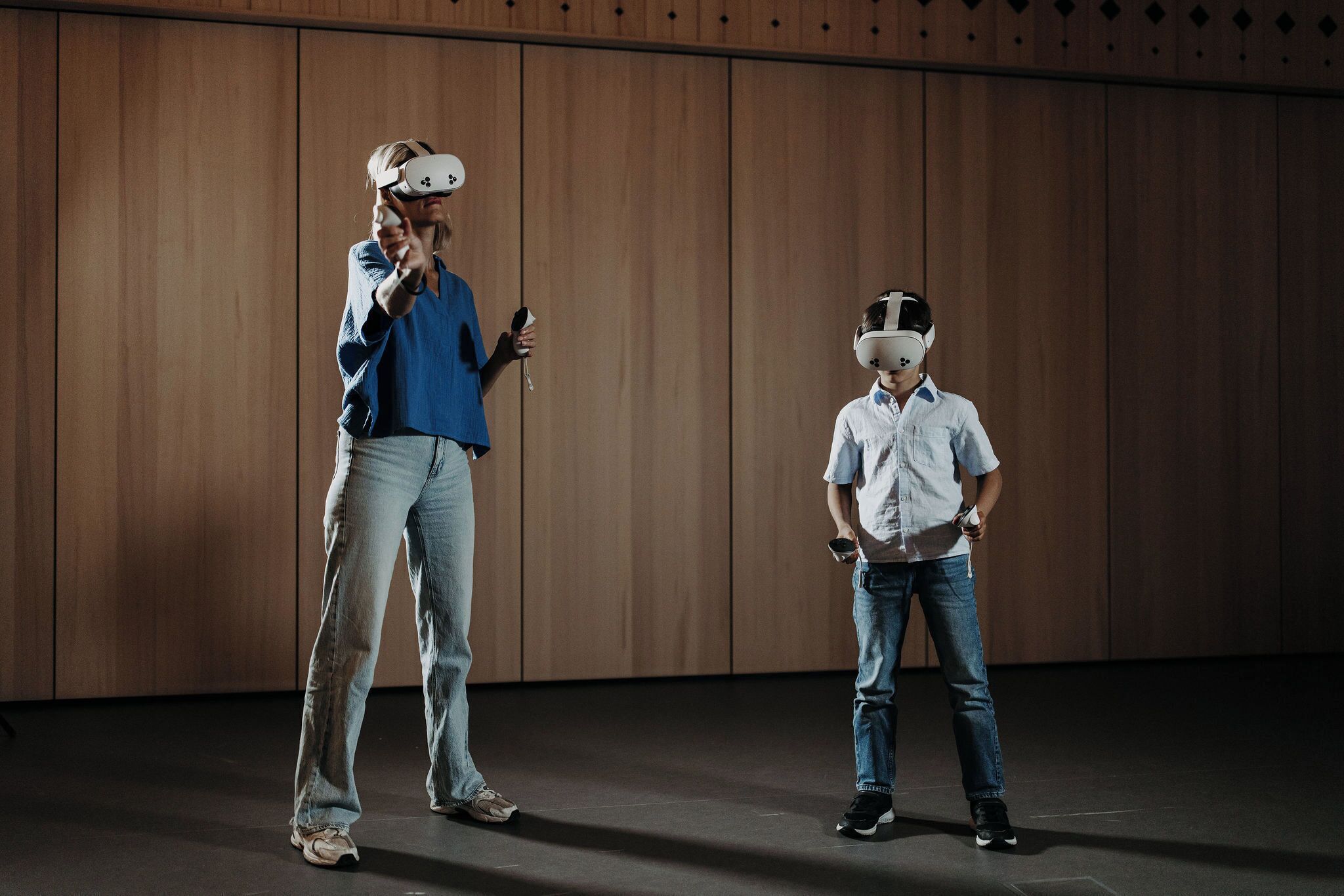 Zwei Personen mit VR-Brillen in einem Raum mit Holzvertäfelung.