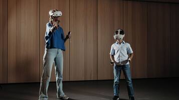 Zwei Personen mit VR-Brillen in einem Raum mit Holzvertäfelung.
