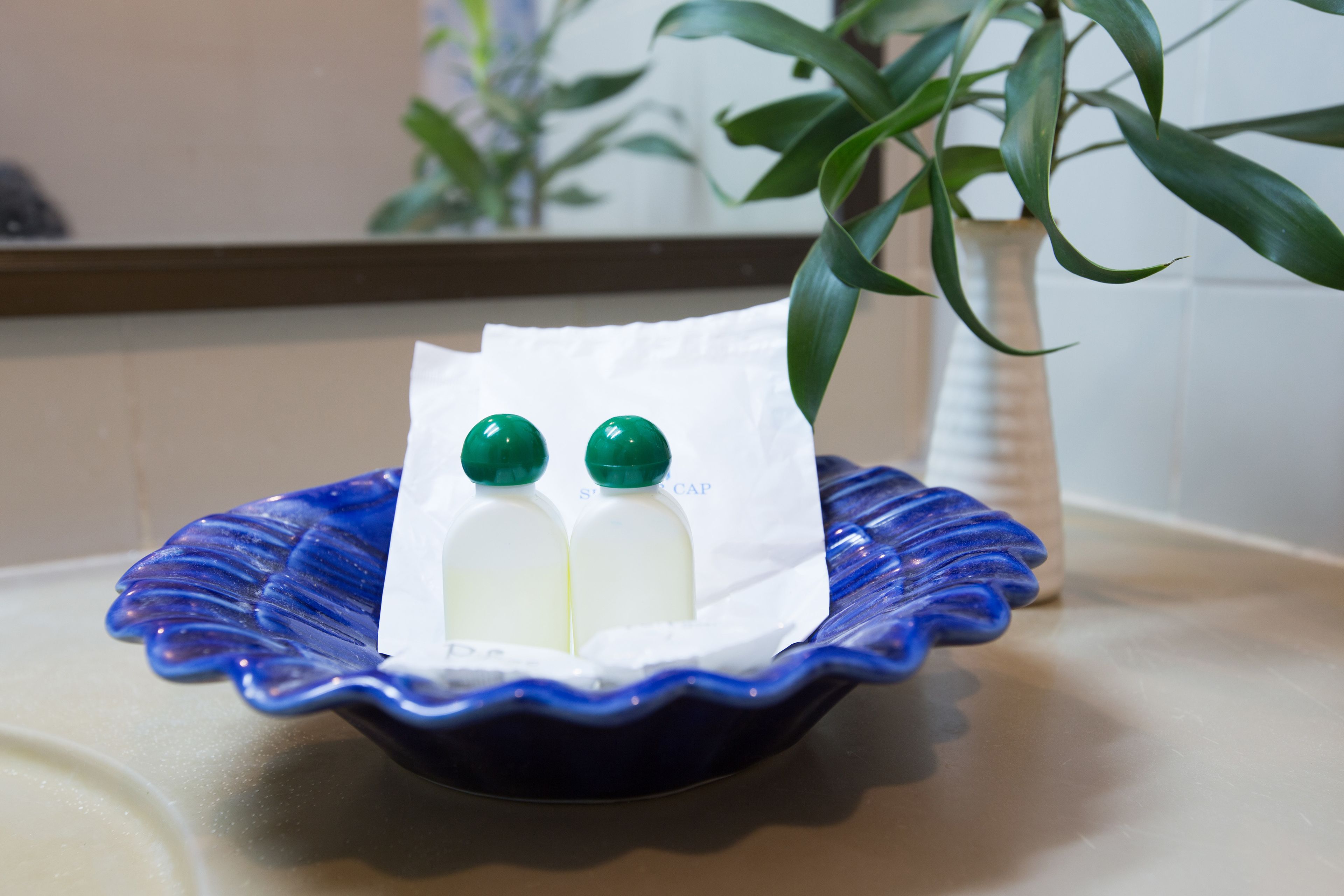 A blue ceramic dish with two white bottles and a white paper with text on a countertop.