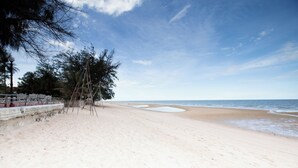 Una playa con arena, algunos árboles y un cielo despejado.