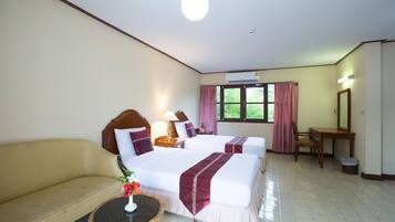 A hotel room with two beds, a sofa, a small table with a vase, a desk, and a chair.