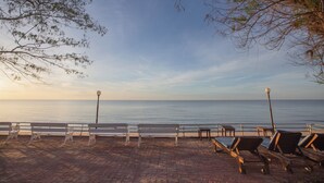 Un paseo marítimo con bancos y tumbonas a lo largo del camino, con vistas al mar tranquilo.