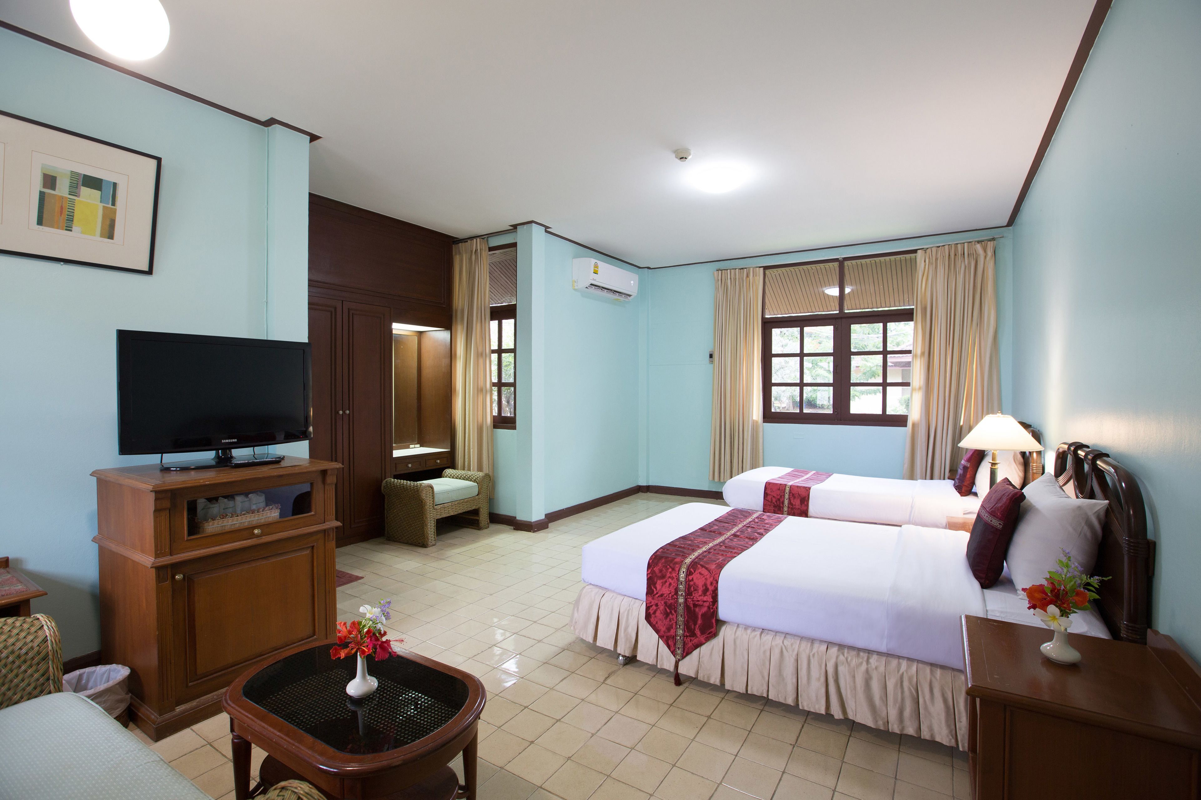 A hotel room with two beds, a television, a desk, and a chair.