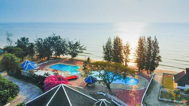 Una propiedad costera con piscina, sombrillas y vistas al mar.