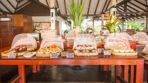 A buffet table with various food items covered with protective netting, a large potted plant, and a sign indicating the buffet section. - Centara Chaan Talay Resort & Villas (Trat)