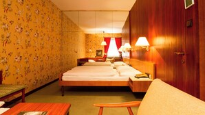 Ein Hotelzimmer mit floralem Wanddesign, einem Bett, einem Schreibtisch und einem Stuhl.