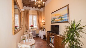 A cozy room with a dining area, a television, and a painting on the wall. - Relais Centro Storico Pisa (Pisa)