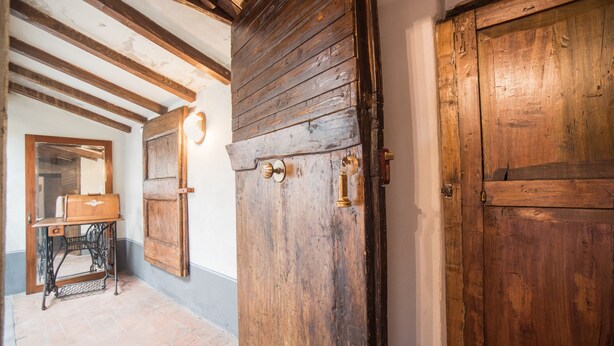 A rustic interior with exposed wooden beams, a vintage sewing machine, and a large wooden door. - Relais Centro Storico Pisa (Pisa)