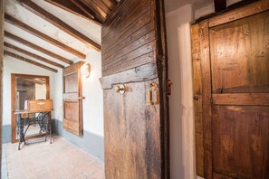 A rustic interior with exposed wooden beams, a vintage sewing machine, and a large wooden door. - Relais Centro Storico Pisa (Pisa)